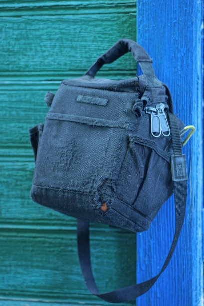 蓝绿色的木墙上挂着一个破洞的旧黑色布袋图片下载