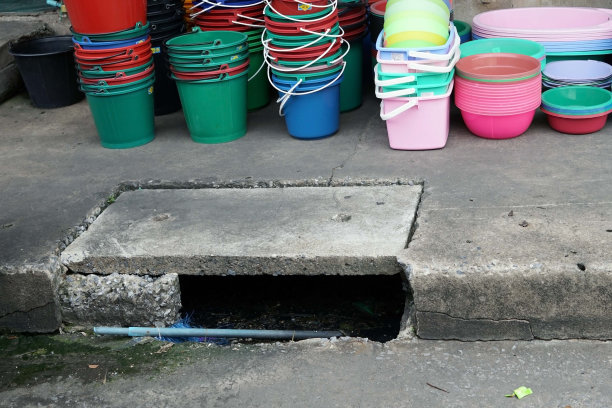 一个塑料桶和塑料杯放在街道附近的混凝土地板上出售。图片下载