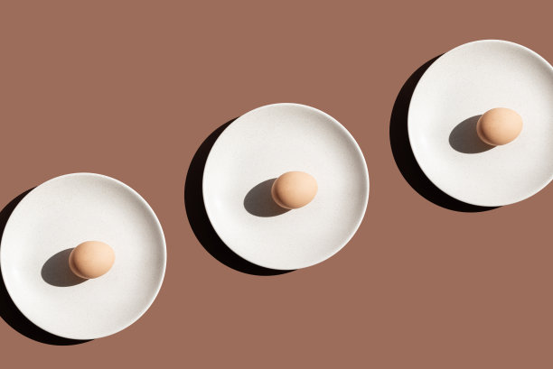 鸡蛋在棕色背景上的图案。俯视图，米色盘子上的生鸡蛋。原色照片图片下载