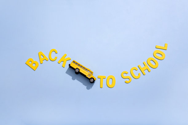 在黄色的背景上，一辆黄色的校车，上面有回学校的路标。概念图。图片下载