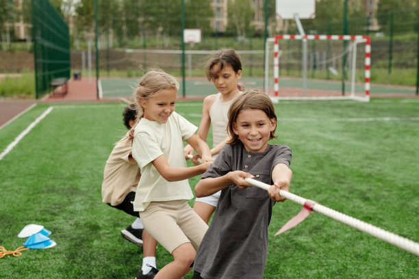 快乐可爱的跨文化同学穿着运动服拉着绳子图片下载