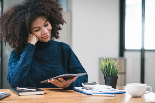 非裔美籍商人或会计，留着非洲发型，使用计算器、图表和图表分析市场数据、资产负债表、账目和净利润。图片下载