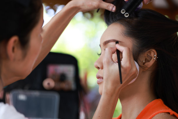 化妆师和她的模特在外面工作，化妆师和客户一起工作。年轻的女时装模特正在准备化妆。图片下载