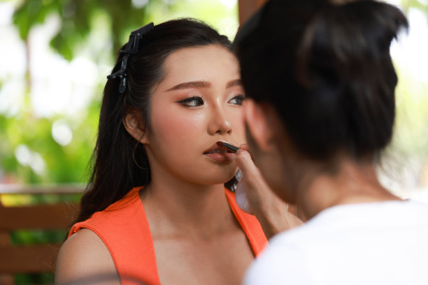 化妆师和她的模特在外面工作，化妆师和客户一起工作。年轻的女时装模特正在准备化妆。图片下载