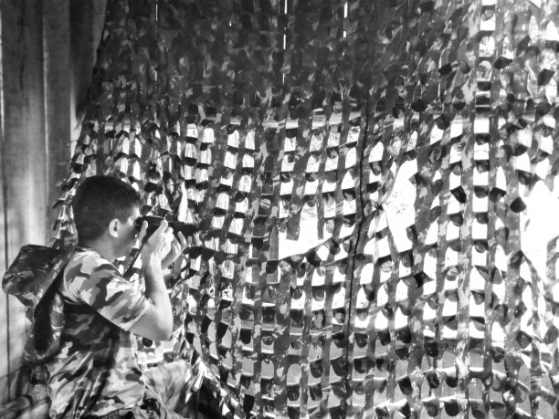 摄影师穿着迷彩服，在森林中央的一间小木屋里图片下载