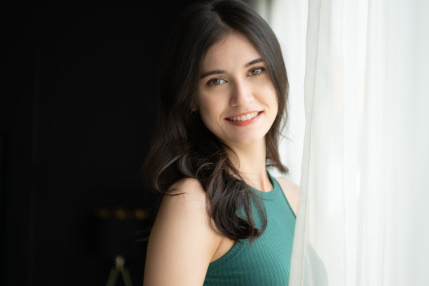 一个穿着绿色衬衫的亚洲美女站在窗边图片下载