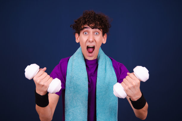 有趣的情绪化的家伙在健身。学生在蓝色背景上摆姿势。图片下载