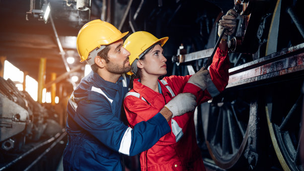 铁路工程师队伍穿着安全制服和安全帽，在列车，车轮和控制系统下进行安全旅行乘客的检查。横幅封面设计。图片下载