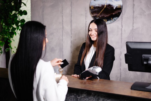 女士用信用卡对着读卡器支付酒店服务费用图片下载