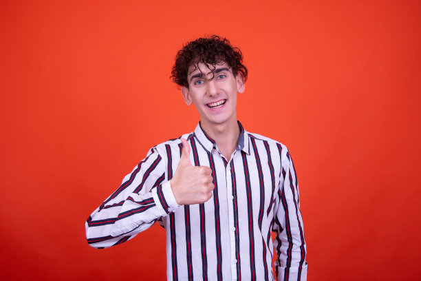 年轻有吸引力的情绪化的家伙在工作室里摆姿势，背景是橙色的。图片下载