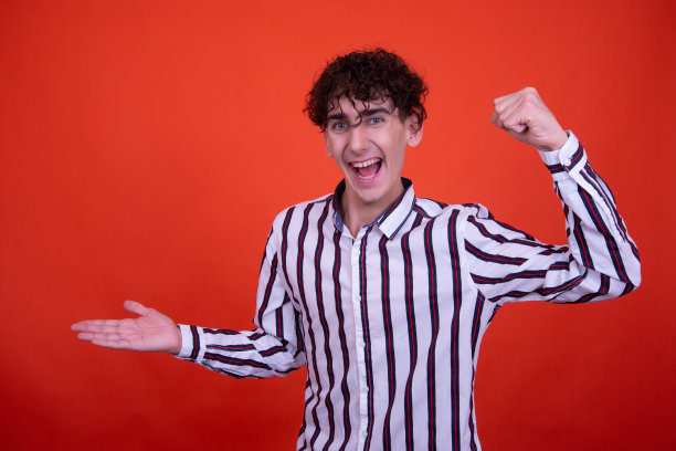 年轻有吸引力的情绪化的家伙在工作室里摆姿势，背景是橙色的。图片下载