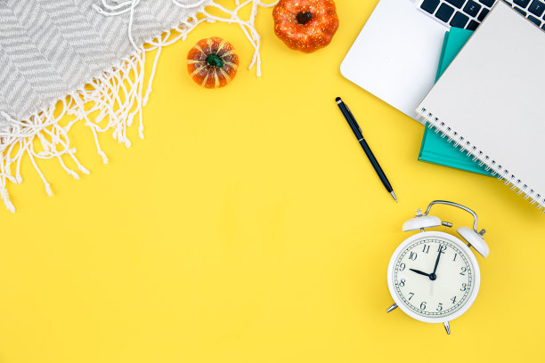 笔记本电脑，闹钟和记事本在黄色背景。图片下载