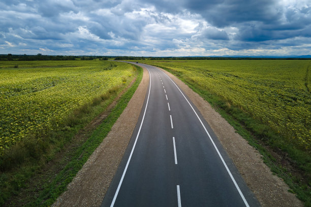 绿色农田之间空荡荡的城际道路鸟瞰图。从无人机俯瞰高速公路图片下载