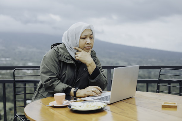 坐在阳台上使用笔记本电脑的穆斯林妇女图片下载