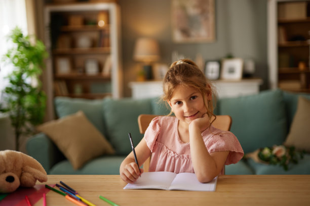 一个小女孩在家里用彩色铅笔画画的肖像图片下载