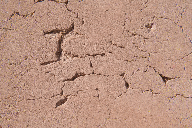 背景图片显示了新墨西哥州一座老教堂里的一面纹理丰富、有裂缝的质朴灰泥砖墙，上面点缀着稻草——这是一种传统建筑材料图片下载