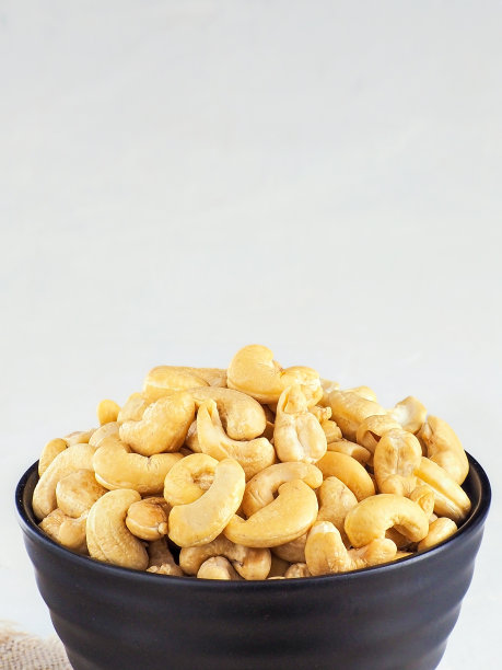 黑色碗或盘子里的去壳腰果。正面前视图。腰果宣传照片与复制空间。图片下载