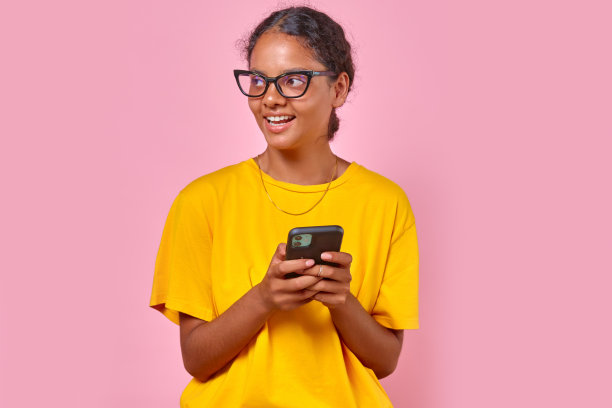 年轻乐观的印度女子戴着时髦的眼镜，站在工作室里拿着手机图片下载