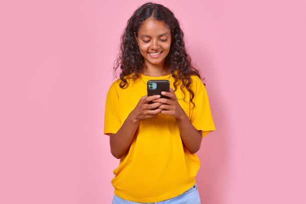 年轻、微笑、美丽的印度少女正在用手机发信息图片下载