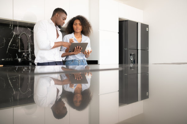 这对年轻夫妇在家里的厨房里用笔记本电脑讨论生意。图片下载