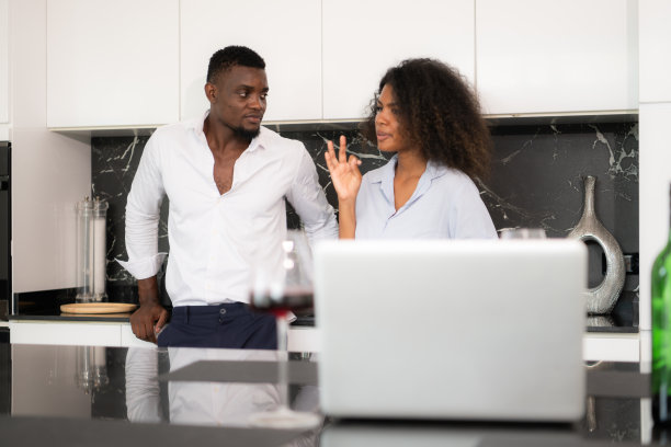 这对年轻夫妇在家里的厨房里用笔记本电脑讨论生意。图片下载