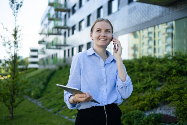 成功的专业房地产经纪人的肖像是在电话上，在大城市的户外繁忙的街道上用数码平板电脑为客户电话预约。图片下载