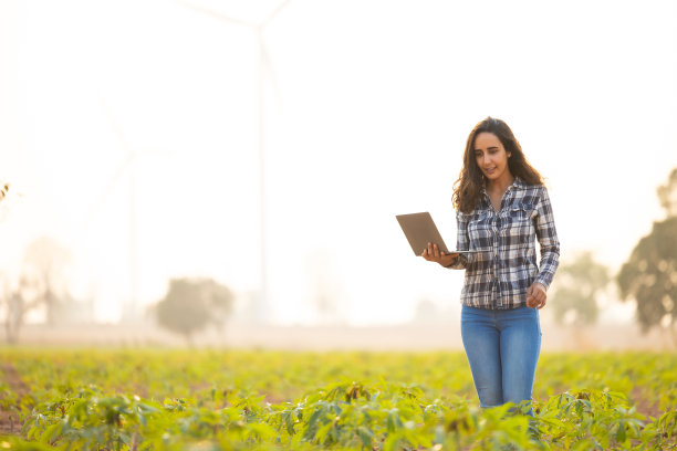 西班牙裔妇女农民手里拿着笔记本电脑研究可持续性和增长分析。农业、种植园和园艺概念图片下载