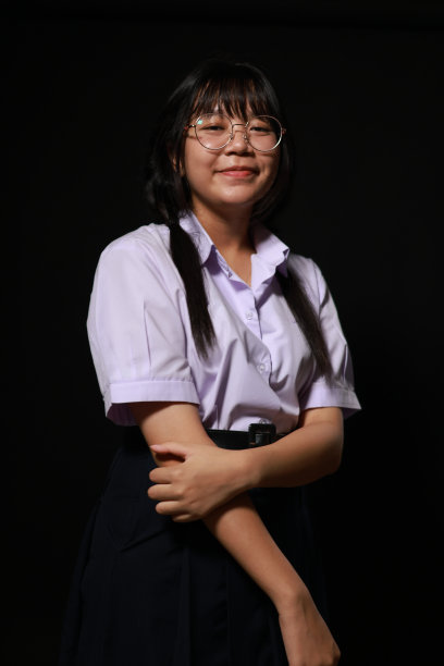 微笑的脸。年轻的亚洲女学生穿着校服，戴着黑色背景的眼镜。女学生肖像，工作室横幅标题。学校孩子的脸，拷贝空间。图片下载