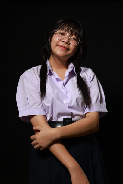 微笑的脸。年轻的亚洲女学生穿着校服，戴着黑色背景的眼镜。女学生肖像，工作室横幅标题。学校孩子的脸，拷贝空间。图片下载