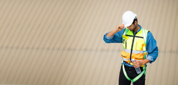 累了热了擦汗。电气工程师西班牙裔男子在屋顶建筑工地喝水。在屋顶安装太阳能电池。太阳能是清洁绿色的替代能源概念图片下载