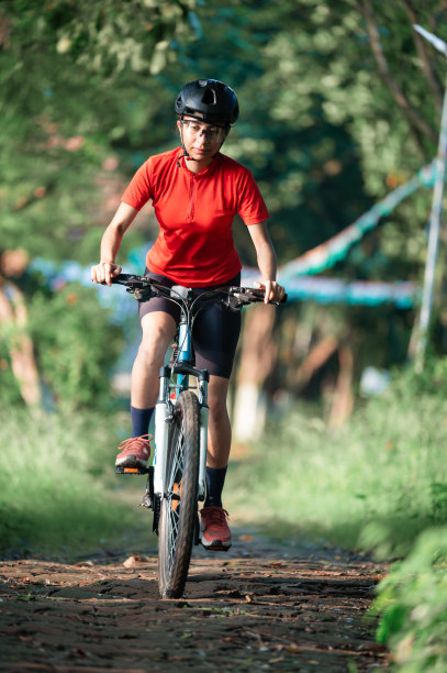 年轻的女子骑着她的山地车在夏日的森林小径上享受美丽的骑行图片下载
