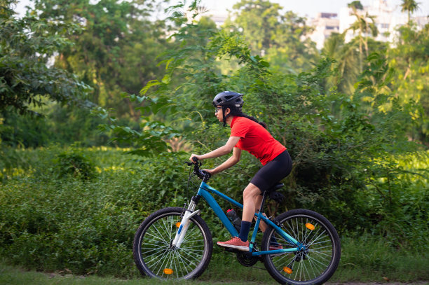 年轻的女子骑着她的山地车在夏日的森林小径上享受美丽的骑行图片下载
