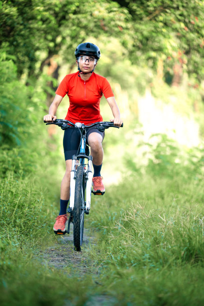 年轻的女子骑着她的山地车在夏日的森林小径上享受美丽的骑行图片下载