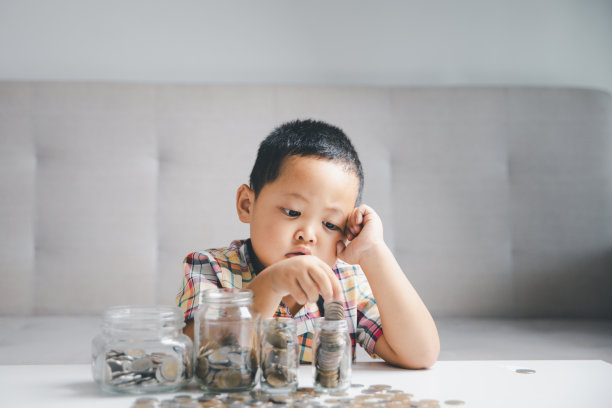 学龄前儿童学习计算个人预算、理财、玩投资、算账。专心读书的孩子存钱买东西，把钱放在家里的粉色存钱罐里。图片下载