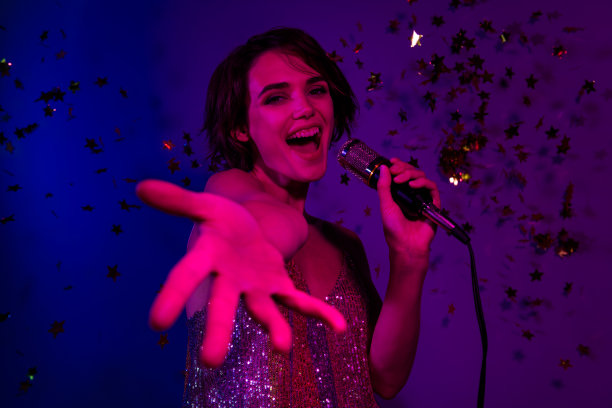 疯狂的流行歌星名人女士在演唱会表演舞台上唱麦克风的照片跟着观众跟我来孤立的霓虹色背景图片下载