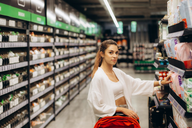 一位年轻的母亲在购物中心的超市里挑选尿布。儿童卫生用品。图片下载