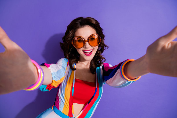 兴奋时髦的女孩穿着条纹整体深色眼镜的照片，自拍孤立的紫色背景图片下载