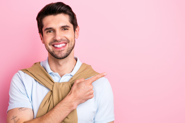 肖像满意高兴的年轻人喜气洋洋的微笑直接手指空白空间信息空白隔离在粉红色的背景图片下载
