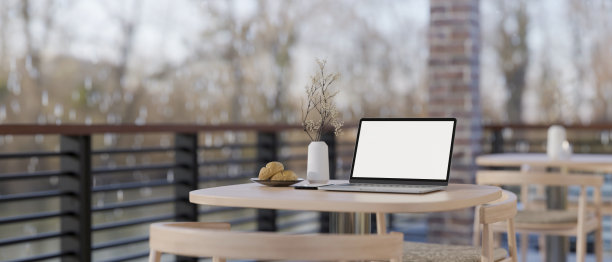 冬日里，在舒适的咖啡馆或餐厅里，阳台上的木桌上放着一台笔记本电脑。图片下载