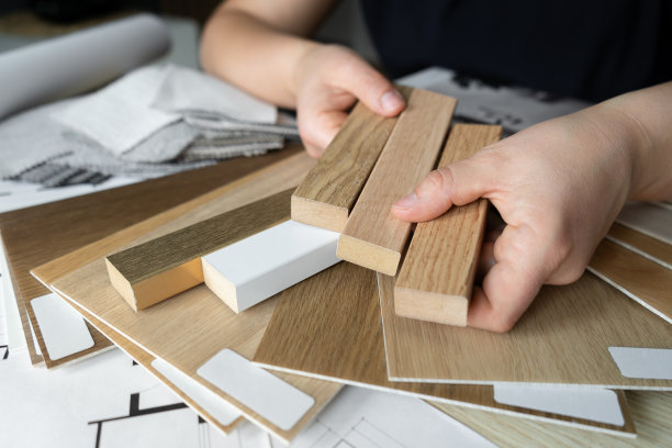 女室内设计师在设计工作室向客户展示木条板和木地板或地板样品。图片下载