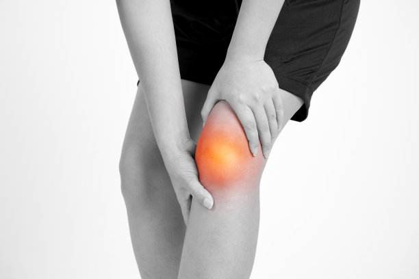一个膝盖疼痛的年轻女人的特写视图。孤立在白色背景。带红点的黑白照片。图片下载