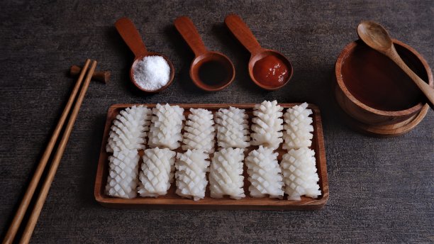 木盘上的鱿鱼花。新鲜的生鱿鱼，经清洗并切成花朵状。枪乌贼寻常的。图片下载