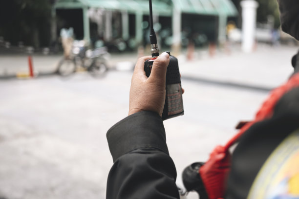 保安使用无线电通讯，方便交通。泰国，交通警察在停车场用对讲机维持秩序。图片下载