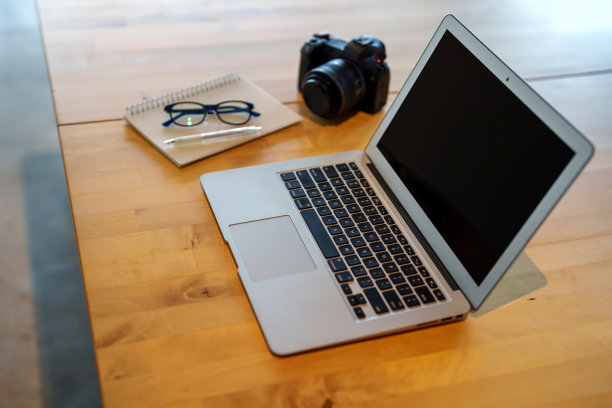 办公室设置的现代工作台，配有笔记本电脑，数码相机，记事本和智能手机。图片下载