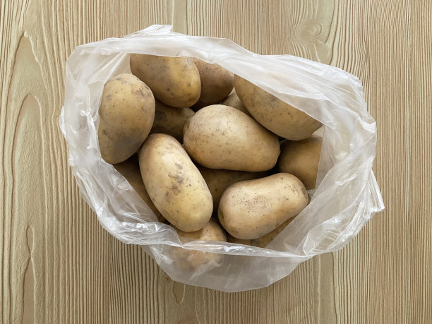 木头背景的塑料购物袋里的土豆图片下载