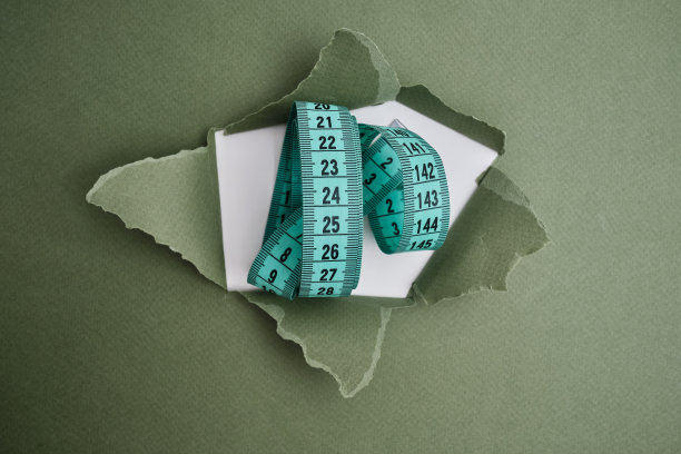 浅色背景上的绿色卷尺。测量长度和体积的工具。用于测量服装行业或人体体积的卷尺图片下载