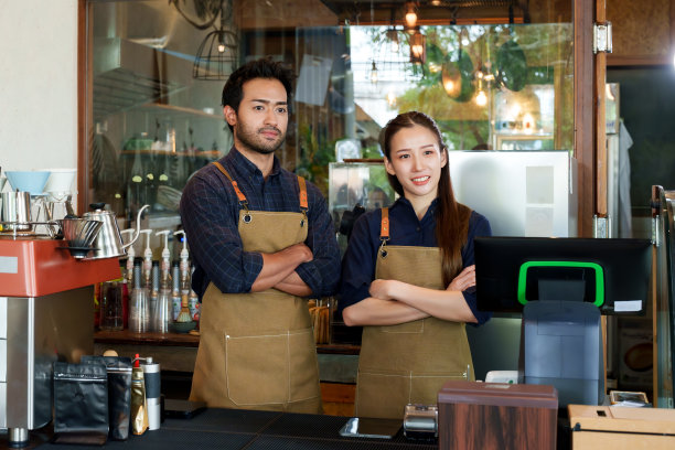 西班牙裔男子和咖啡店老板的妻子站在一起合影，宣传咖啡店。一个小的家庭企业，为社会上的人们互相了解关怀，面对面站着，双臂交叉。图片下载