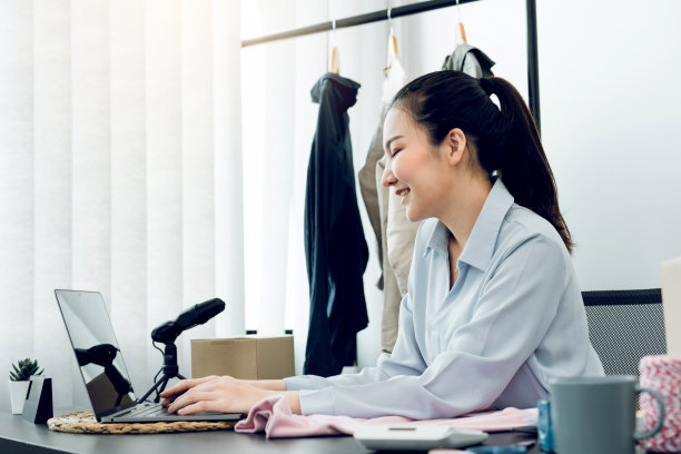 年轻的亚洲企业家在电脑前微笑着与客户聊天。图片下载