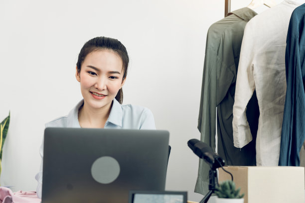 年轻的亚洲企业家在电脑前微笑着与客户聊天。图片下载