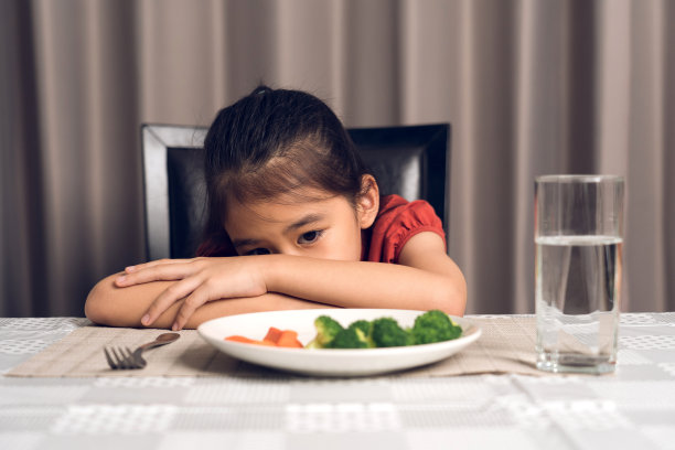 可爱的小女孩拒绝吃健康的蔬菜。孩子们不喜欢吃蔬菜。图片下载